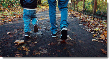 Father and son waking on the park - picture just showing legs and feet